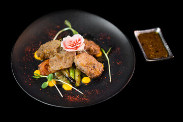 close up of an exquisite serving of a special dish from the chef on a black plate