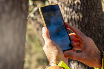 close up, detail of hands holding a smartphone taking pictures outdoors.