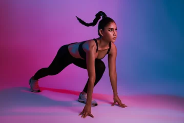  Athlete asian sportswoman running as part of fat burning workout in fitness studio neon background. Woman exercising with cardio at the gym. © NaMong Productions