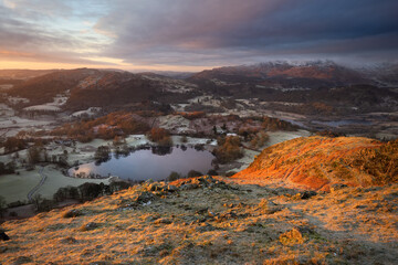 Fototapeta na wymiar A picturesque view taken from Loughrigg Fell overlooking the tarn and snowcapped Cumbrian Fells. Taken on a frosty Winter morning. Lake District, UK.