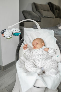 Adorable baby sleeps in baby rocker in room. Newborn concept.