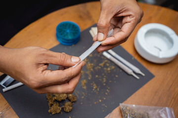 Young man making cigarettes with medical marijuana