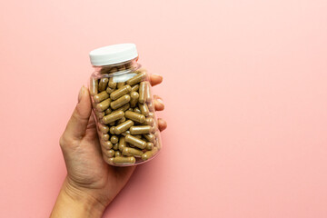 Hand holding a jar with ashwagandha capsules, immunity support, health care, body supplementation