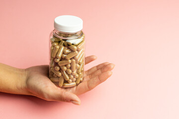 Hand holding a jar with ashwagandha capsules, immunity support, health care, body supplementation