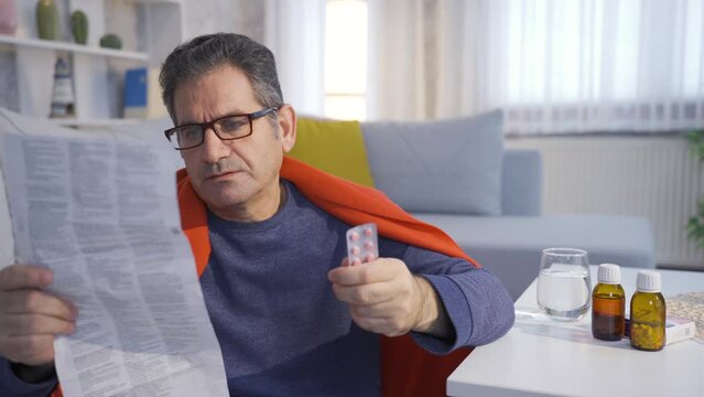 Sick and exhausted man reading the prospectus of the medicinal drugs he will use.
Sick mature man is sluggish and exhausted at home, taking his medications, trying to maintain his health.
