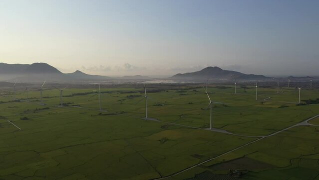 Aerial view of windmills farm for energy production on rice field, Dam Nai, Ninh Thuan, Vietnam. Wind power turbines generating clean renewable energy for sustainable development