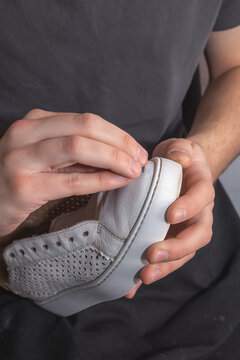 Shoemaker's hands sanding an old sneaker with sandpaper before painting. Shoe repair. Close-up