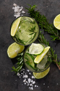 A refreshing and healthy glass of water with cucumbers, fresh citrus lime on a sprig of rosemary