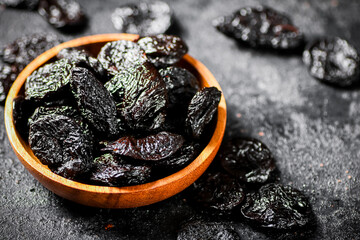 Prunes in a wooden plate on the table. 