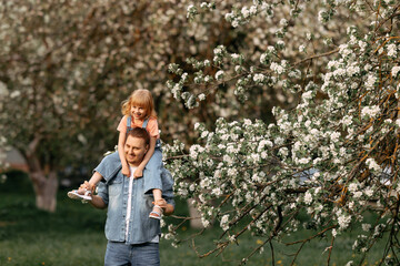 Dad and daughter are hugging under an apple blossom tree.