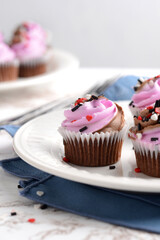 valentines day cupcakes with heart sprinkles and blue napkin