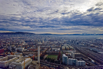 Aerial view of City of Zürich seen from industrial district with Lake Zürich and Swiss Alps in the background on a cloudy winter day. Photo taken December 20th, 2022, Zurich, Switzerland.