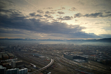 Naklejka na ściany i meble Aerial view of City of Zürich seen from industrial district with Lake Zürich and Swiss Alps in the background on a cloudy winter day. Photo taken December 20th, 2022, Zurich, Switzerland.