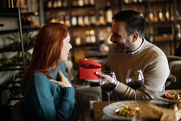 Valentines day couple sitting in favourite caffe, exchanging gifts in hart shape, couple cudling and hugging