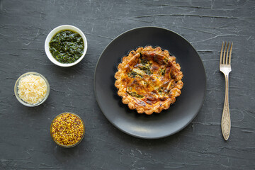 Tasty asparagus tart with cheese and spices on black background, top view. 