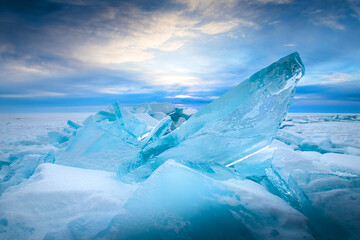 Blue transparent ice on Baikal lake at sunrise.