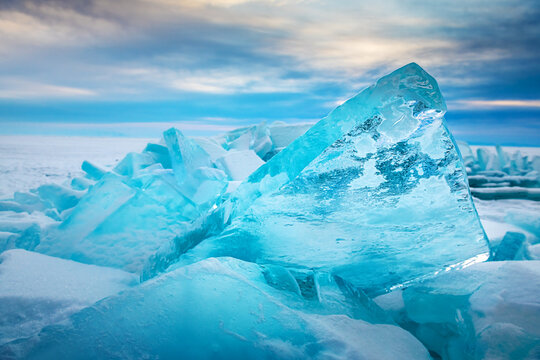 Blue transparent ice on Baikal lake at sunrise.