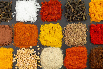 Different spices portioned in square shapes, on black background