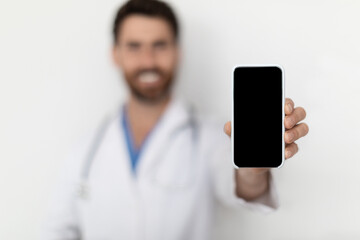 Check This. Smiling Male Doctor Demonstrating Blank Smartphone At Camera