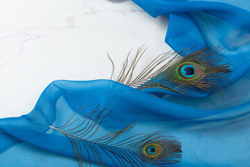 two peacocks feather on blue cloth and white marble