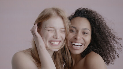 Candid portrait of two beautiful 20s females, African-American Black and Caucasian, posing against solid background, no make-up, studio shot, soft lighting