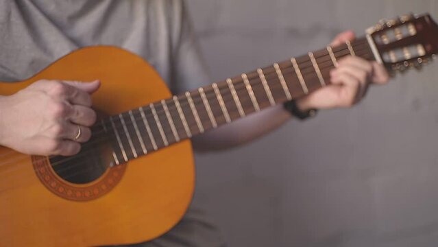 a man in a gray T-shirt rhythmically plays the guitar. High quality Full HD video recording