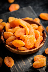 Dried apricots in a wooden plate on the table. 