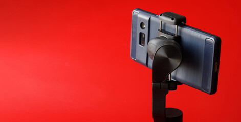 Modern smartphone on gimbal selfie stick for photo-video filming on a mobile phone. Gadgets for blogging, live streaming, journalism and videoconferencing. Copy space. Selective focus.