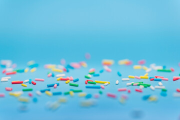 colorful sprinkles over blue background, copy space