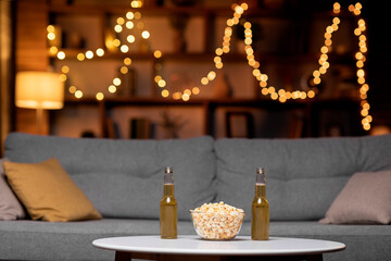 Glass bowl of popcorn and two bottles of beer