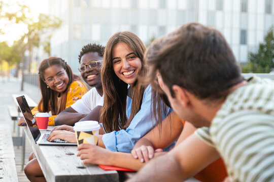 Group of five friends having fun together - students talking laughing and enjoying their time - focus on girl - education concept