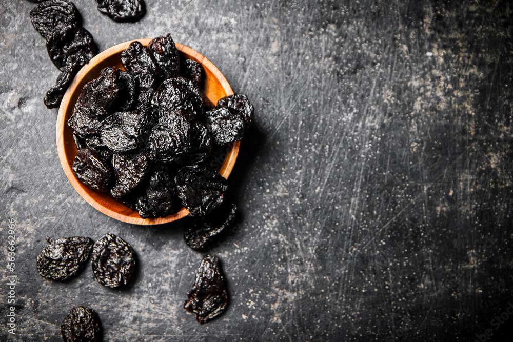 Wall mural Prunes in a wooden plate on the table. 