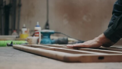 Working process in the carpentry workshop. Carpenter checks the quality sanding wooden board. Profession, joinery, woodwork and people concept