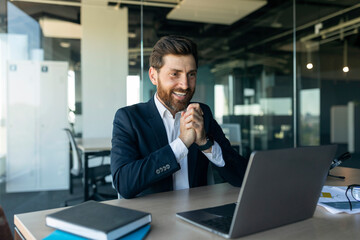 Overjoyed middle aged businessman celebrating great news, looking at laptop screen in joy, sitting...