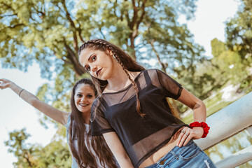 Two sisters enjoying a sunny day at a park. Young sisters at the park. Twin teenage girls enjoying sunny day at a lake.