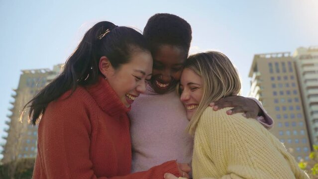 Three female friends affectionately hug each other having fun together laughing happy smiling. Collective lovely embrace concept. High quality 4k footage