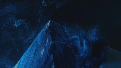 Paint splash. Smoke pyramid. Ink water. Ice hill. Defocused blue color steam floating over frozen glass cube angle edge on dark abstract background.