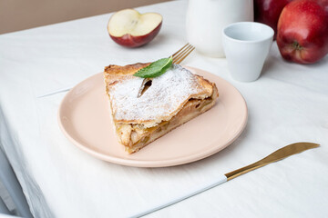 Homemade piece of apple pie with fresh red apples on white table