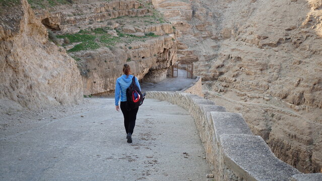 A hiker walking down to the Monastery of Saint George of Choziba in Wadi Qelt in Area C of the eastern West Bank in the Jericho Governorate of the State of Palestine in the month of January
