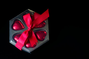 present on a black background, heart-shaped bombomes with a red ribbon . background for valentine's day mother's day