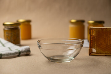 Craft honey. A transparent bowl with honey jars and honeycombs in the background
