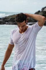 Handsome , good looking, young man with wet shirt posing in the sea, at the tropical beach