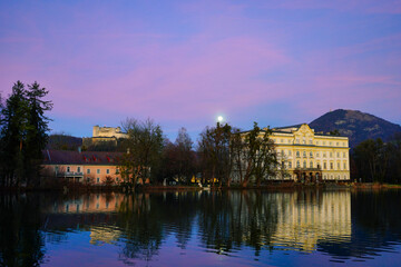 Naklejka na ściany i meble Full moon comes over the castle by the lake. Behind the Salzburg Fortress. 