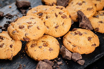 Cookies with pieces of milk chocolate on a stone board. 