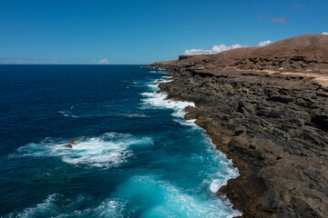 Beautiful landscape with deep blue water. Powerful waves crash against black volcanic rocks on the coast of ´Aguas Verdes, Fuerteventura island. Selective focus, blurred background.