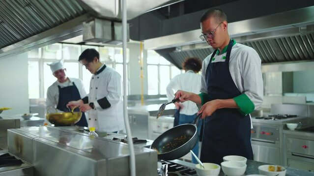 Professional chef cooking at ketchen together. Team of professional cooks in uniform preparing meals for a restaurant in kitchen.