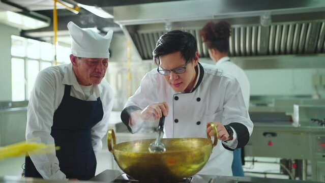Team professional chef cooking at ketchen together. Team of professional cooks in uniform preparing meals for a restaurant in kitchen.