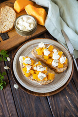 Healthy food, vegetarian appetizer on a rustic table. Open sandwiches whole grain ciabatta with spice pumpkin and feta cheese. Copy space.