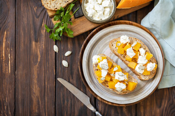 Healthy food, vegetarian appetizer on a rustic table. Open sandwiches whole grain ciabatta with spice pumpkin and feta cheese. View from above. Copy space.