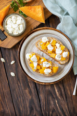 Healthy food, vegetarian appetizer on a rustic table. Open sandwiches whole grain ciabatta with spice pumpkin and feta cheese. View from above. Copy space.